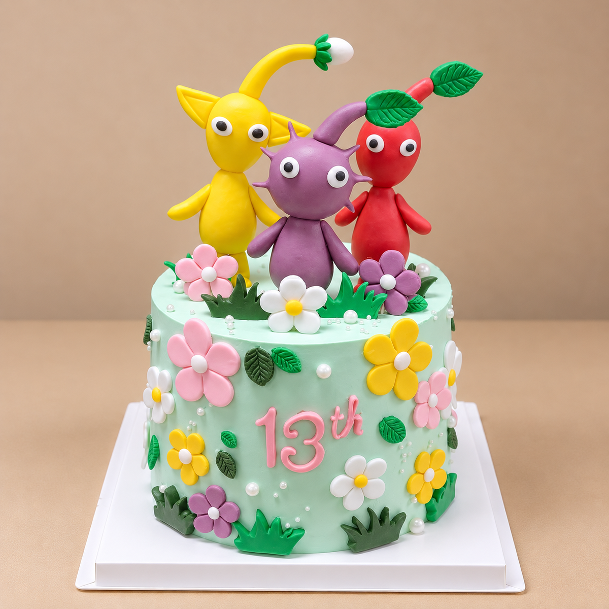 Mint green Pikmin birthday cake with yellow, purple and red character toppers, colourful flowers and pink 13th lettering — Good Day Bakery Singapore
