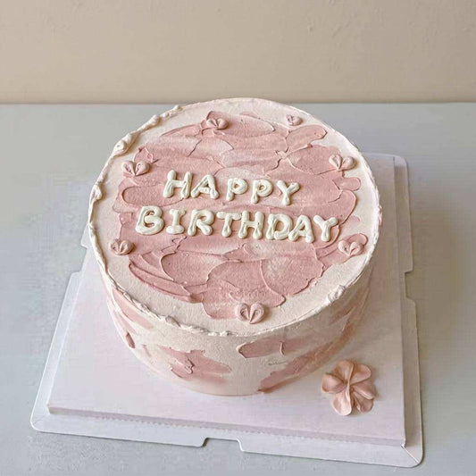 Artistic cake with palette-knife texture and piped happy birthday lettering