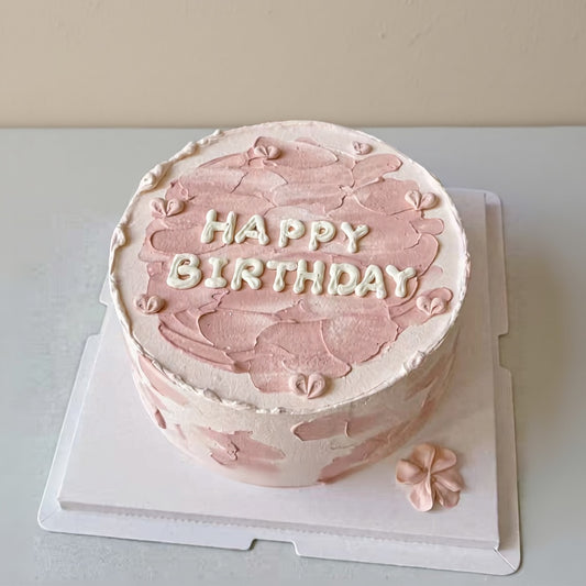 Blush petal cake Singapore with pink frosting and 'Happy Birthday' text on top.