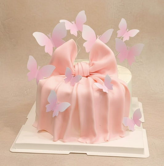 Blushing Butterfly Dream Cake with pink fondant bow and pastel butterflies on top by Good Day Bakery Singapore.