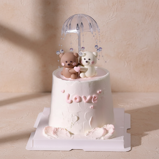 cute bear love cake featuring two fondant bears under an umbrella, decorated with pink accents and crystal-like beads.