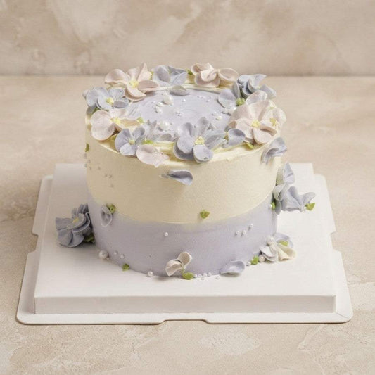 Floral Cake Soft lavender floral meadow birthday cake with two-tone ivory and dusty lavender frosting, decorated with hand-piped buttercream hydrangeas and sugar pearls