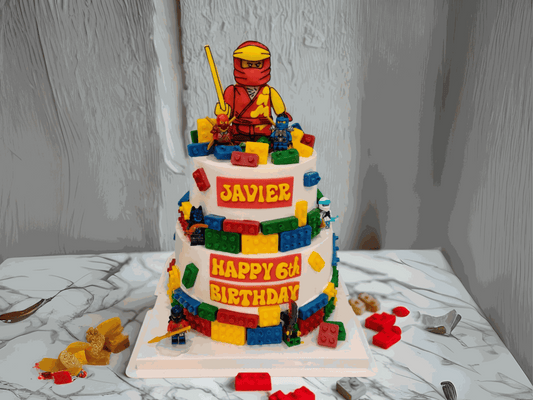 Two-tier ninja cake with red ninja topper and colorful fondant bricks
