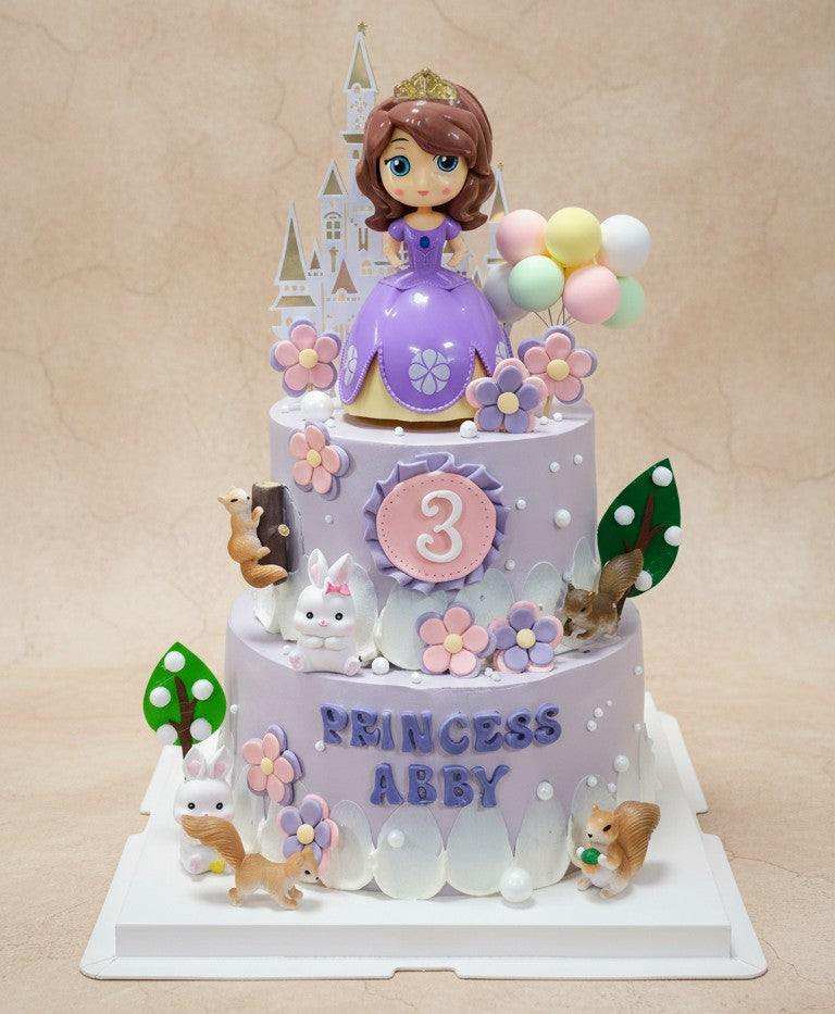 Two-tier enchanted princess cake with Princess Sofia figure and woodland decorations
